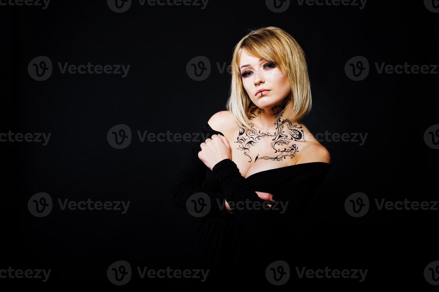 Studio portrait of blonde girl with originally make up on neck, wear on black dress at dark background. photo