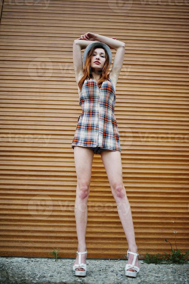 Amazing long legs with hig heels girl wear on hat against shutter. photo