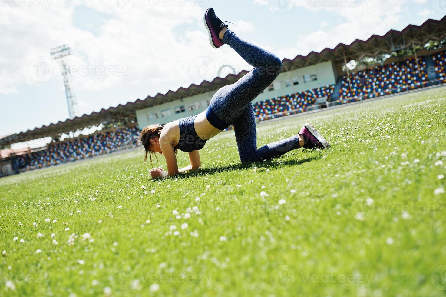 Portrait of a beautiful woman in sportswear stretching her muscles in the stadium. photo