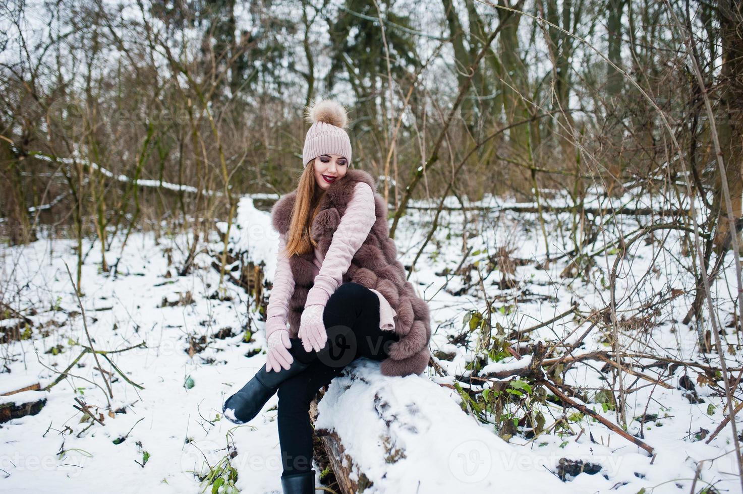 Stylish girl in fur coat and headwear at winter forest. photo