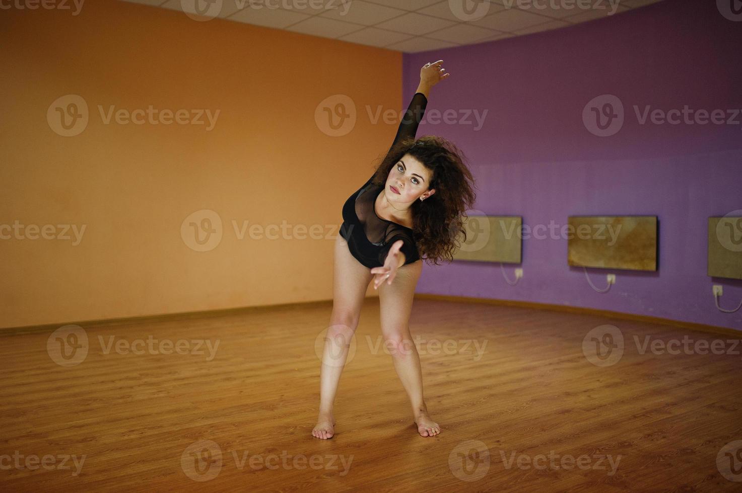 Curly brunette plus size model doing acrobatic at dance room. photo