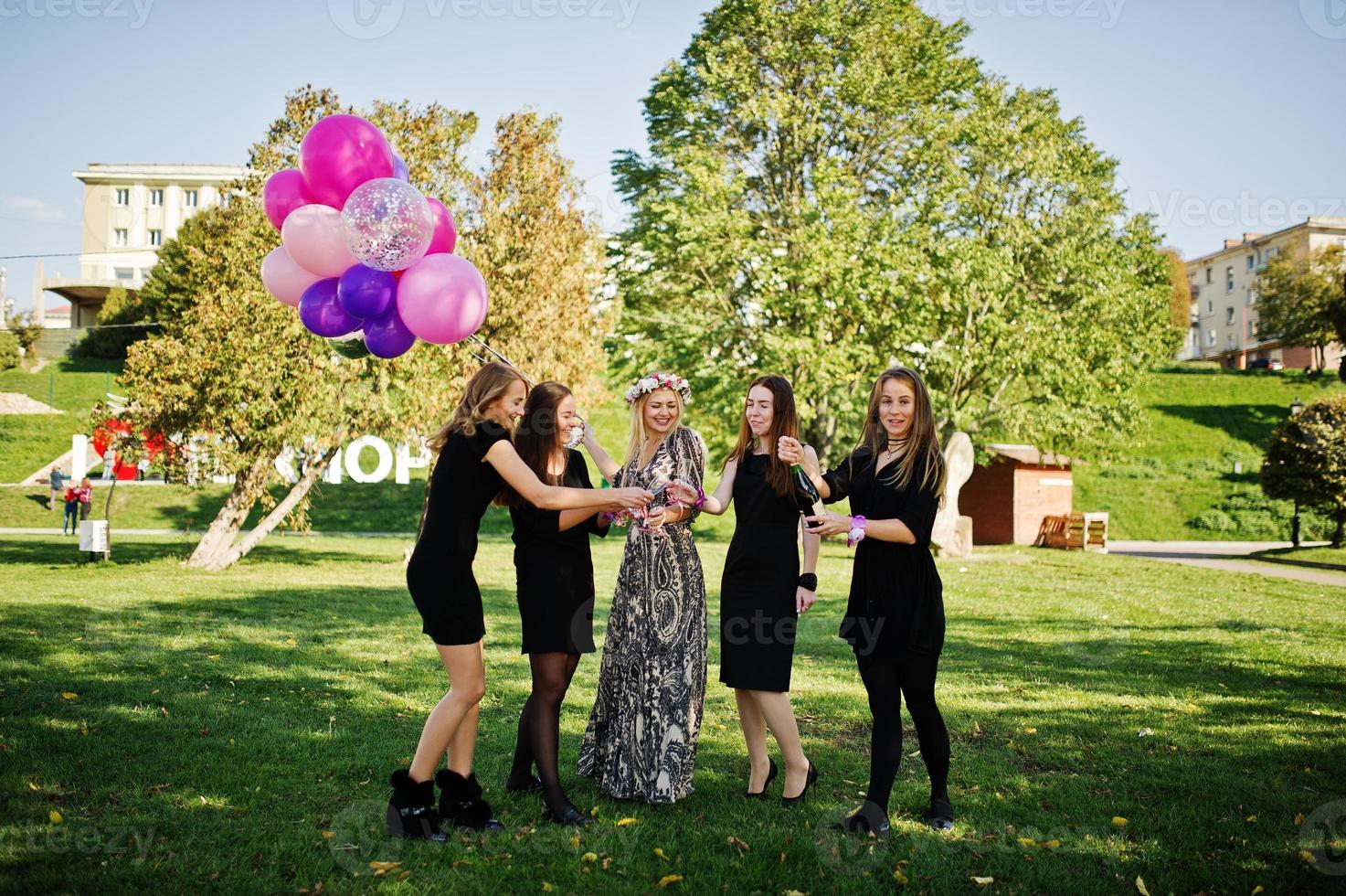 Five girls wear on black with balloons drinking red champagne at hen party. photo