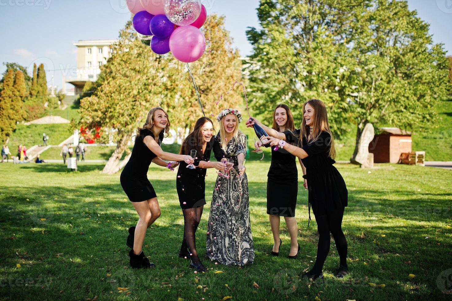 Five girls wear on black with balloons drinking red champagne at hen party. photo