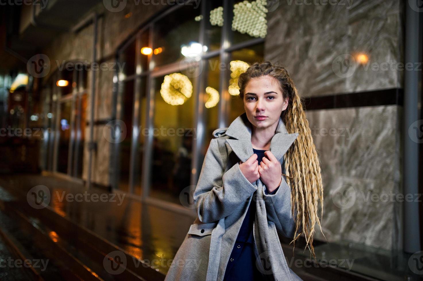 Girl with dreadlocks walking at night street of city. photo