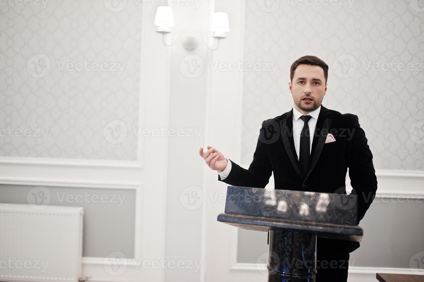 Man well dressed politician speaking behind the podium, public speaker character. photo