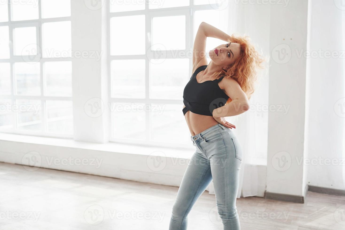 Fitness body type. Attractive redhead woman posing in the spacey room near the window photo