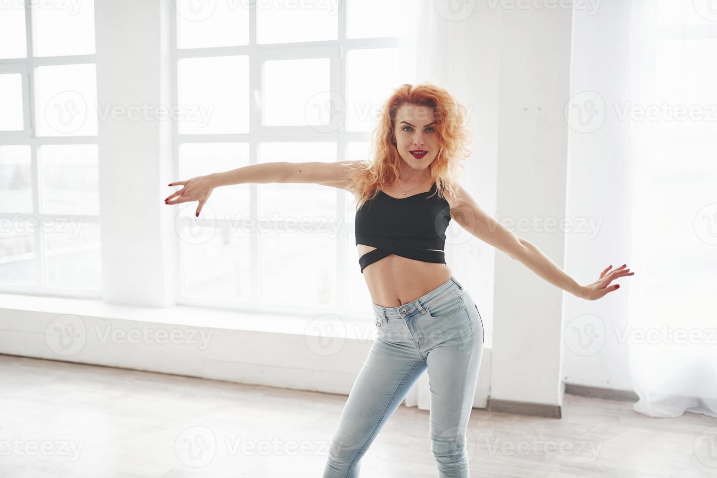Gentle moves. Attractive redhead woman posing in the spacey room near the window photo