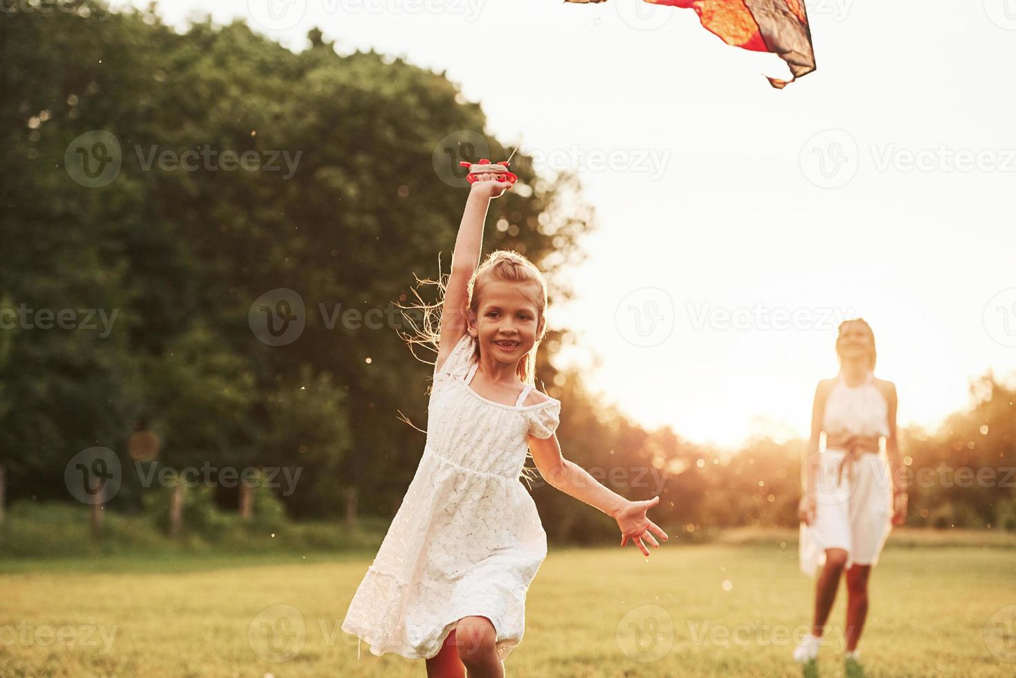 Front view. Mother and daughter have fun with kite in the field. Beautiful nature photo