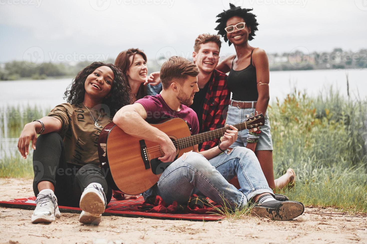 Closeness of people. Group of friends have picnic on the beach. Youth have fun at weekend time photo