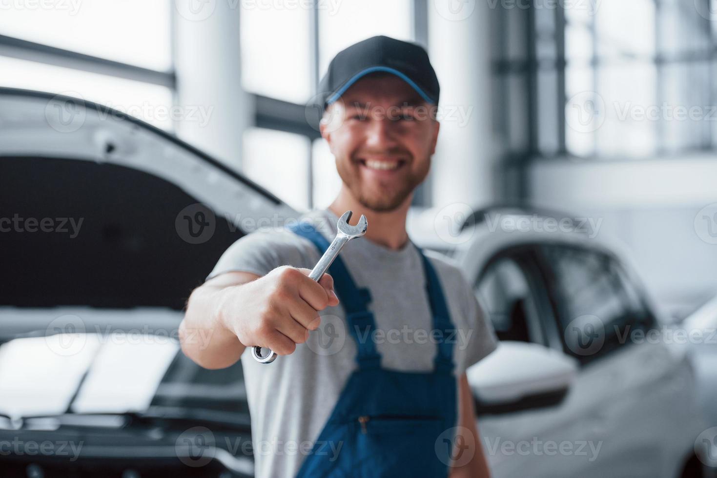 Llámanos si necesitas ayuda. empleado en el uniforme de color azul se encuentra en el salón del automóvil foto