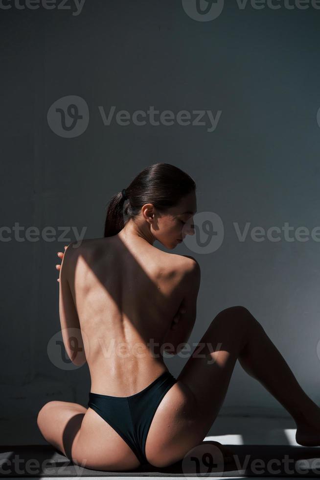 Enjoying morning sunlight. Caucasian pretty woman stands against wall in the studio at daytime photo