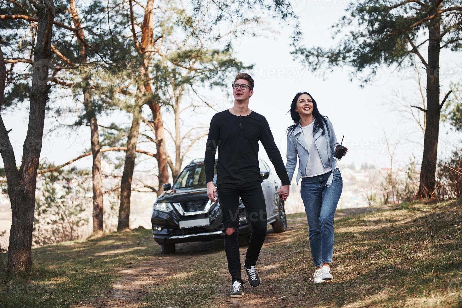 Always together. Embracing and enjoying the nature. Couple have arrived to the forest on their brand new black car photo