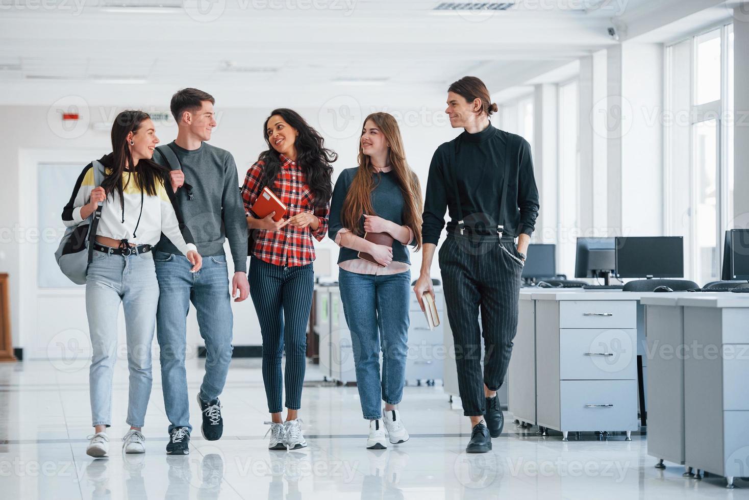 Talking with each other. Group of young people walking in the office at their break time photo