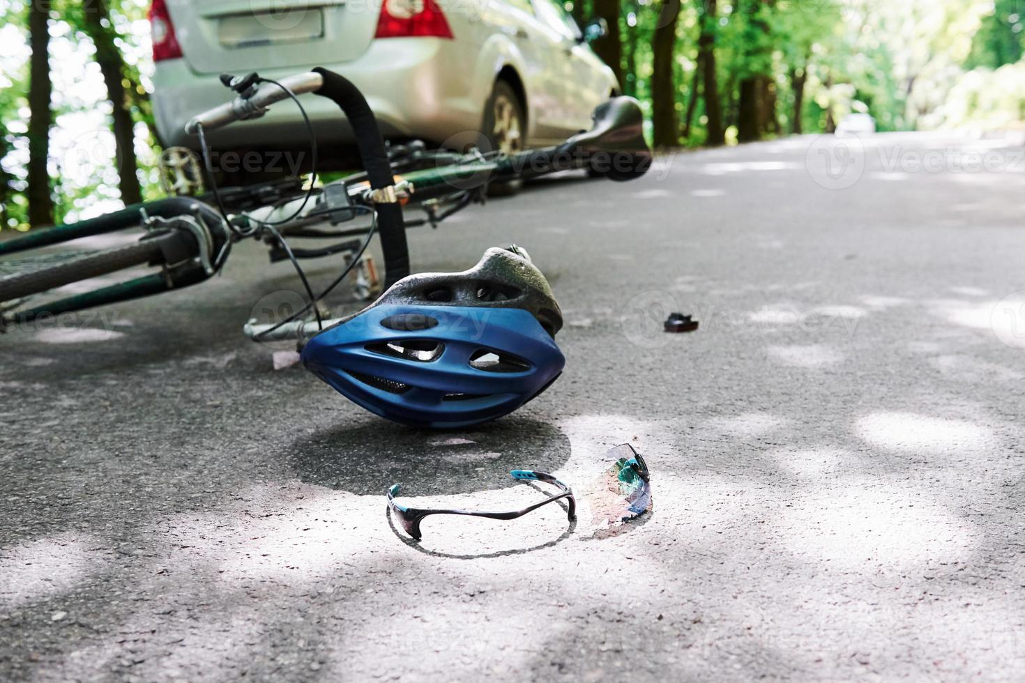 concepción del descuido. bicicleta y accidente automovilístico de color plateado en la carretera en el bosque durante el día foto