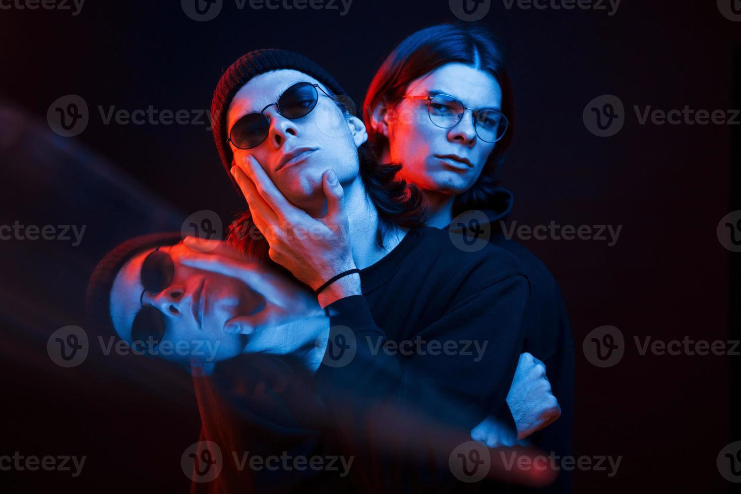 Illusion of three faces. Portrait of twin brothers. Studio shot in dark studio with neon light photo