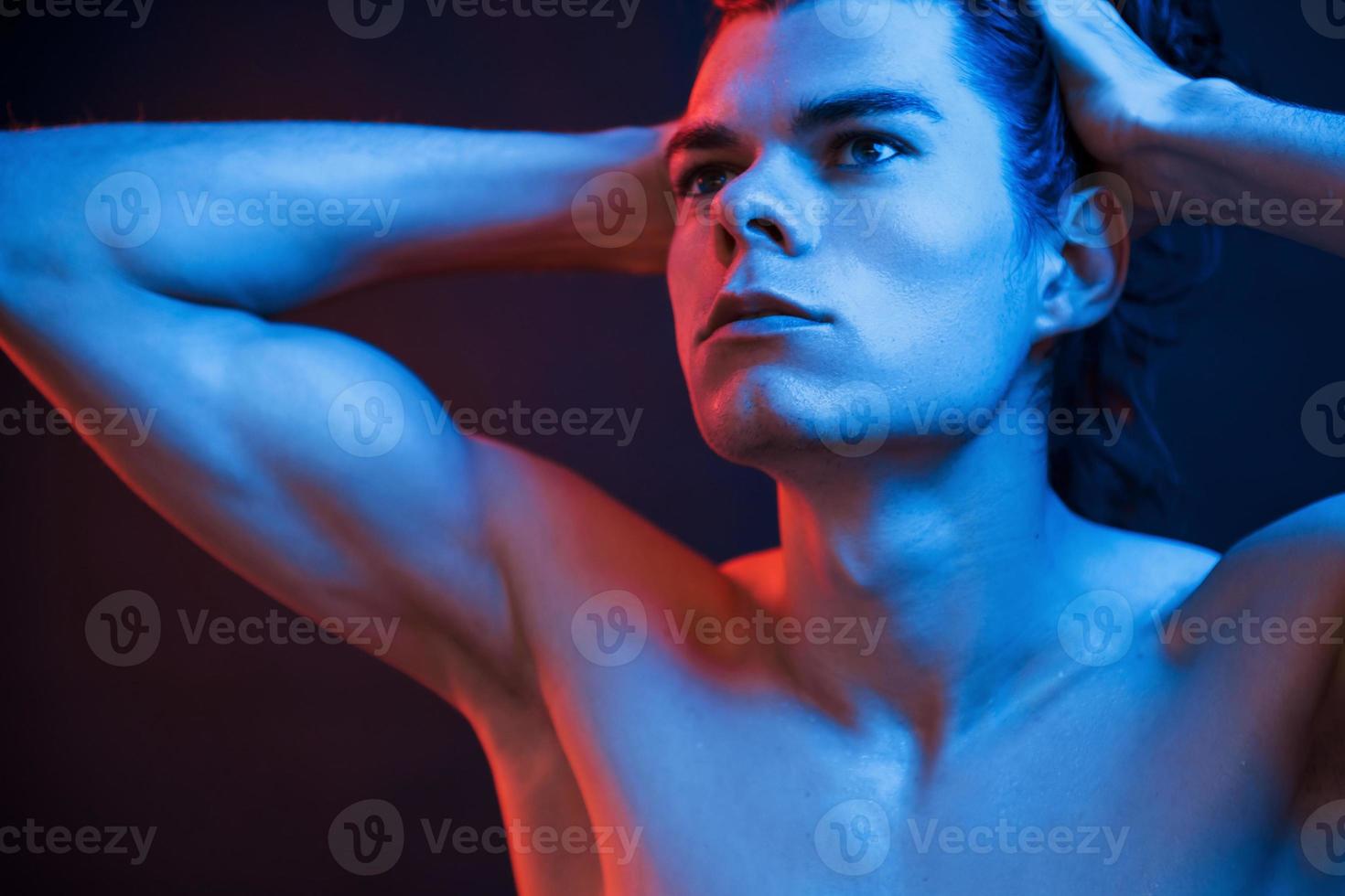 Arms and neck. Studio shot in dark studio with neon light. Portrait of serious man photo