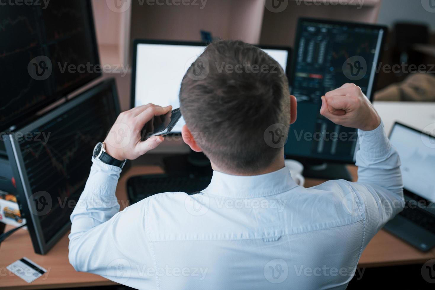 Successful young businessman. Man working online in the office with multiple computer screens in index charts photo