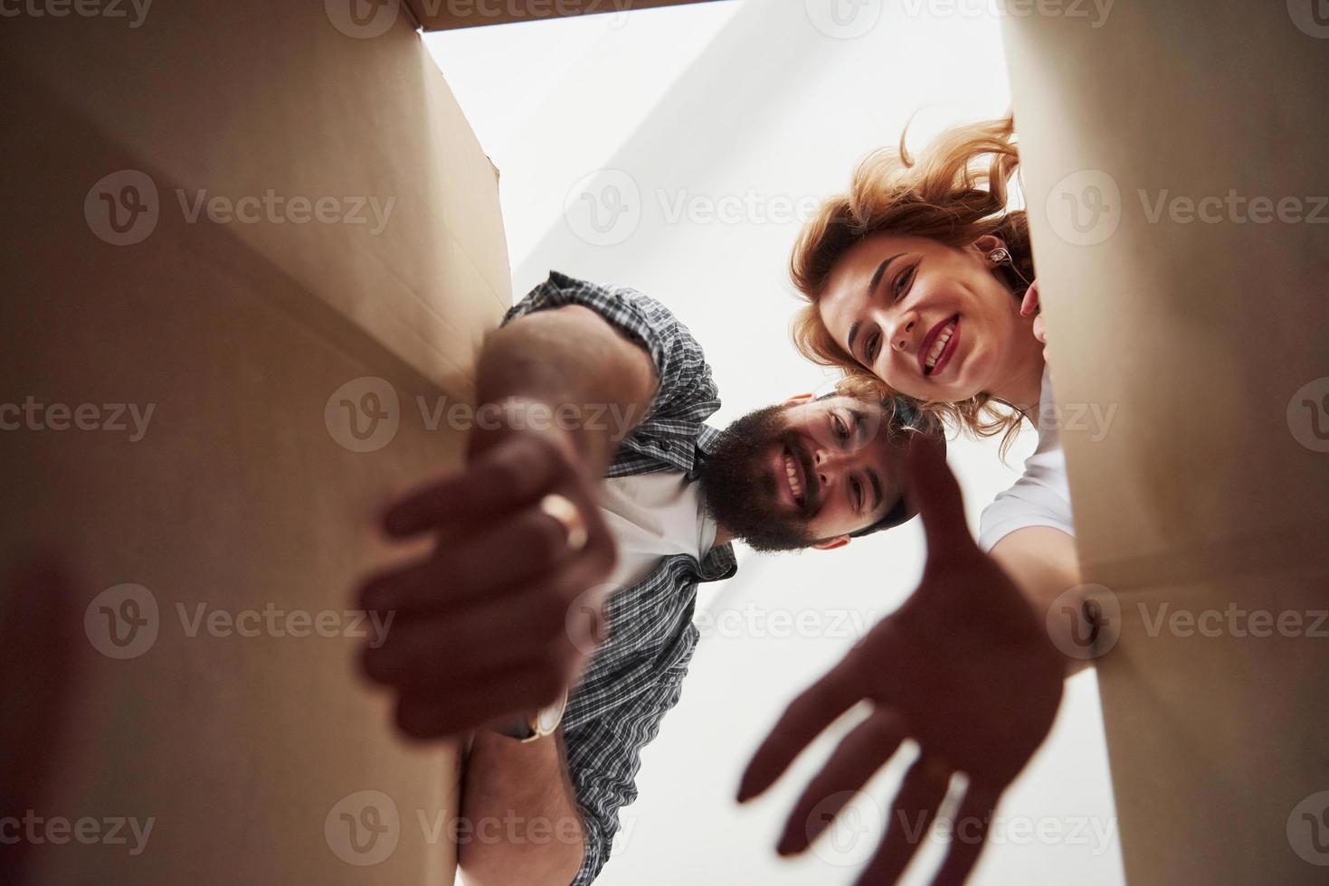 sacando ropa de la caja. pareja feliz juntos en su nueva casa. concepción de movimiento foto