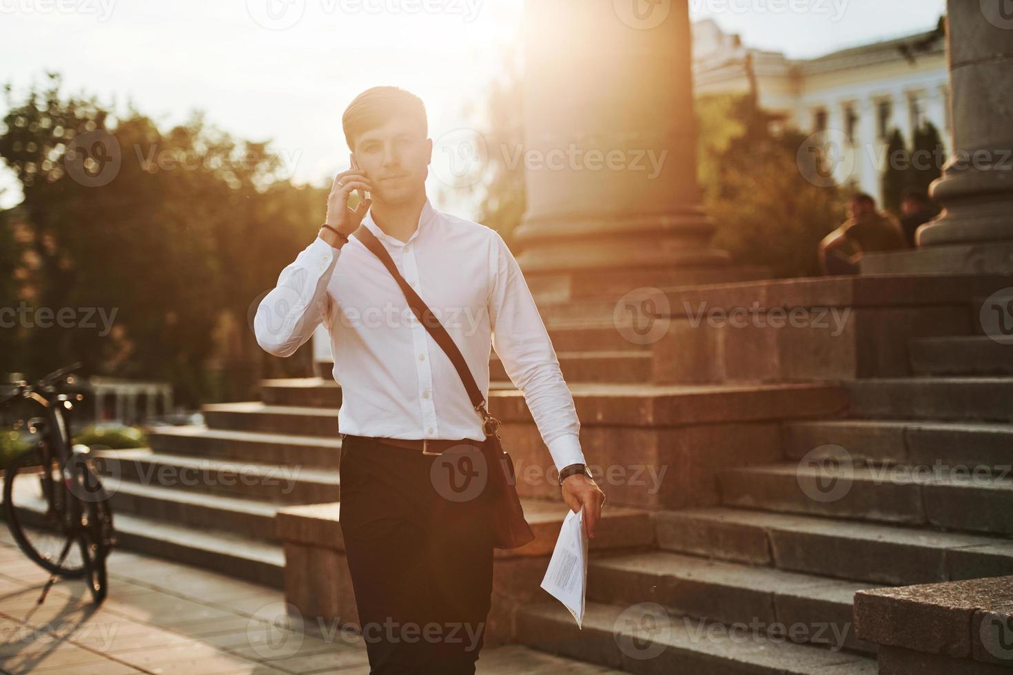 Going forward. Businessman in formal clothes with black bicycle is in the city photo