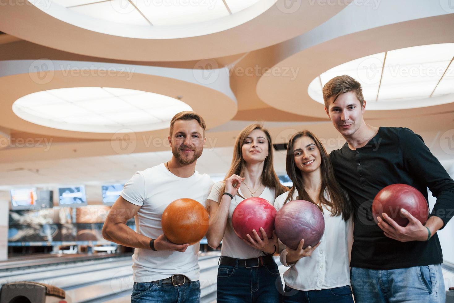 Handsome people. Young cheerful friends have fun in bowling club at their weekends photo