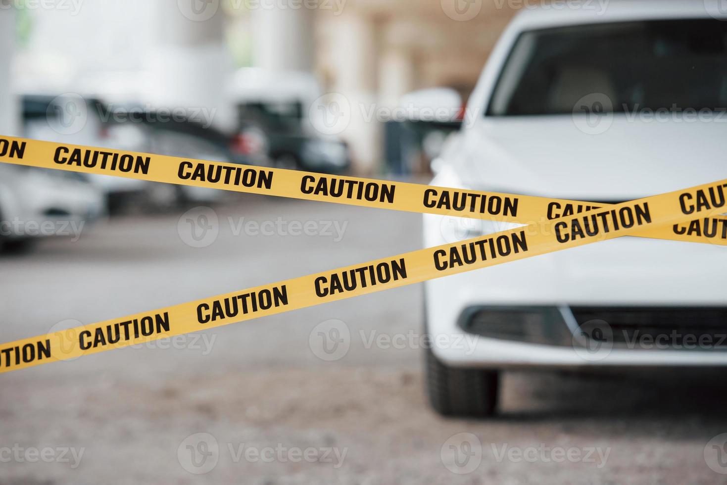 frente del vehículo de lujo moderno. cinta amarilla de precaución cerca del estacionamiento de autos durante el día. escena del crimen foto