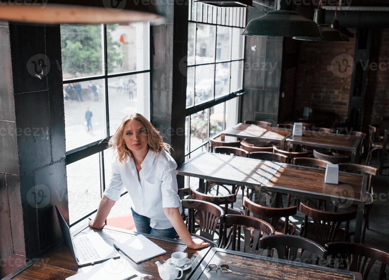 buen humor. mujer de negocios con cabello rubio rizado en el interior de la cafetería durante el día foto