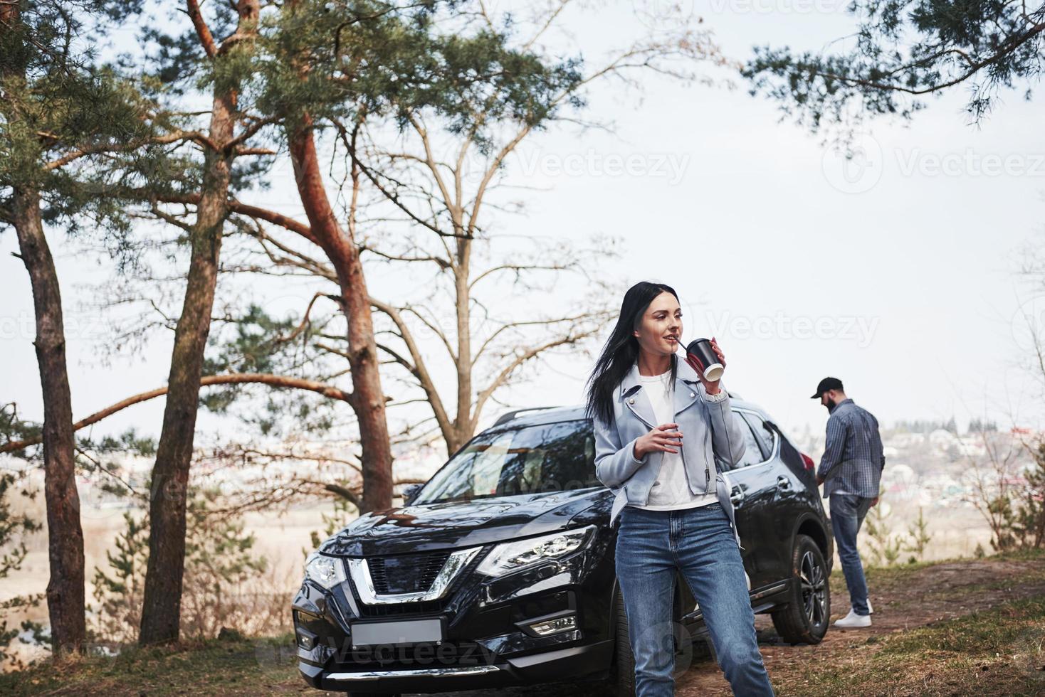 Couple have arrived to the forest on their brand new black car photo