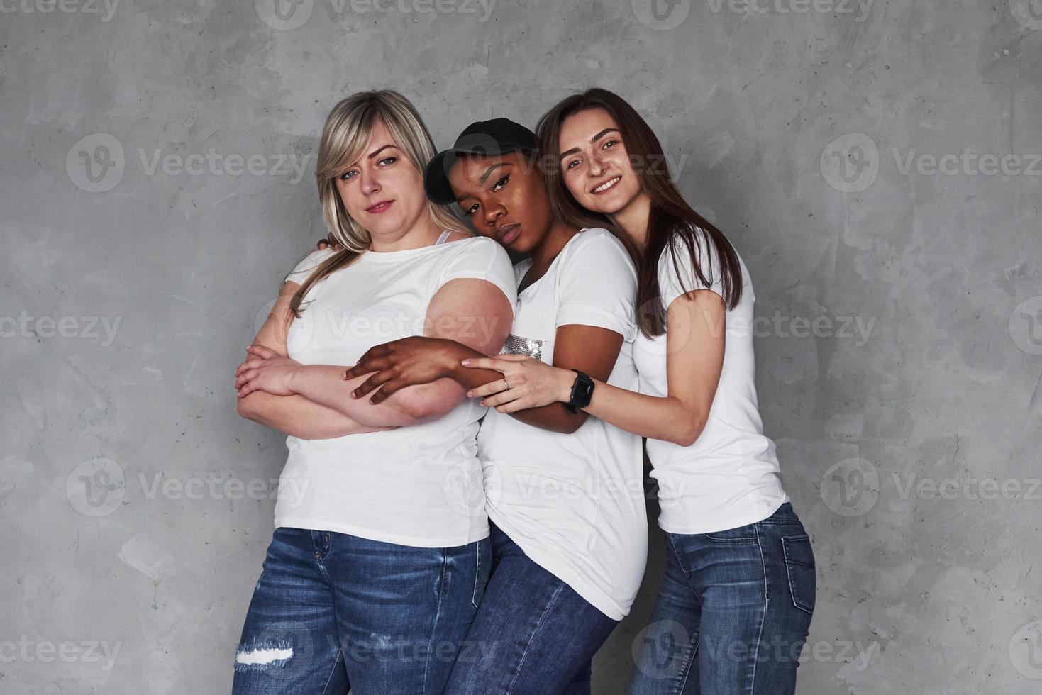 Tired a little. Group of multi ethnic women standing in the studio against grey background photo