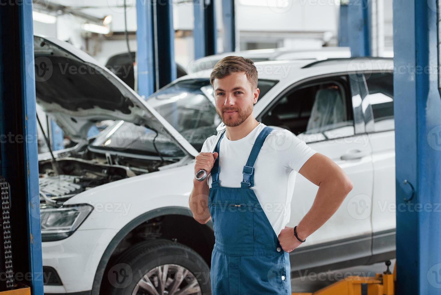 emociones positivas. empleado en el uniforme de color azul trabaja en el salón del automóvil foto