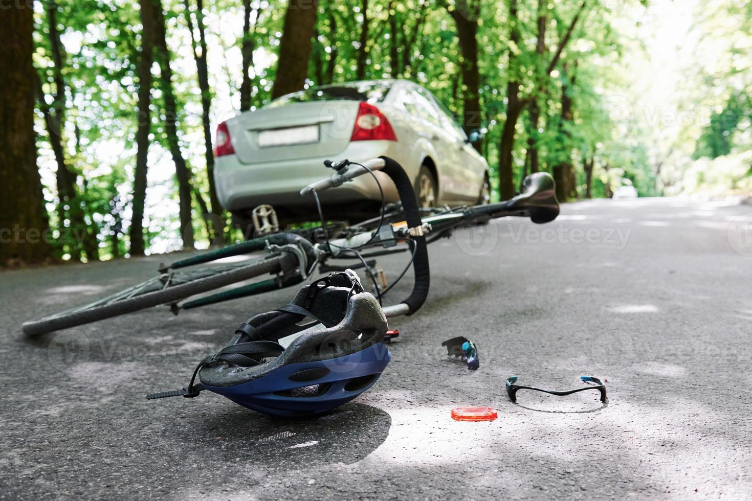 Call an emergency. Bicycle and silver colored car accident on the road at forest at daytime photo