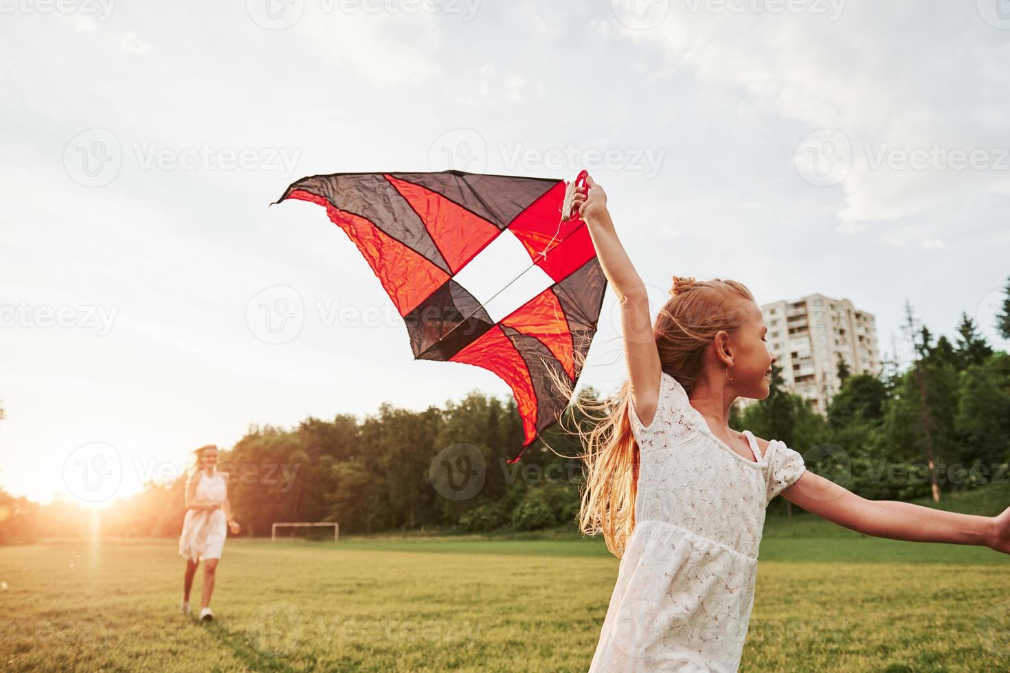 Healthy and active time spending at weekend time. Mother and daughter have fun with kite in the field. Beautiful nature photo