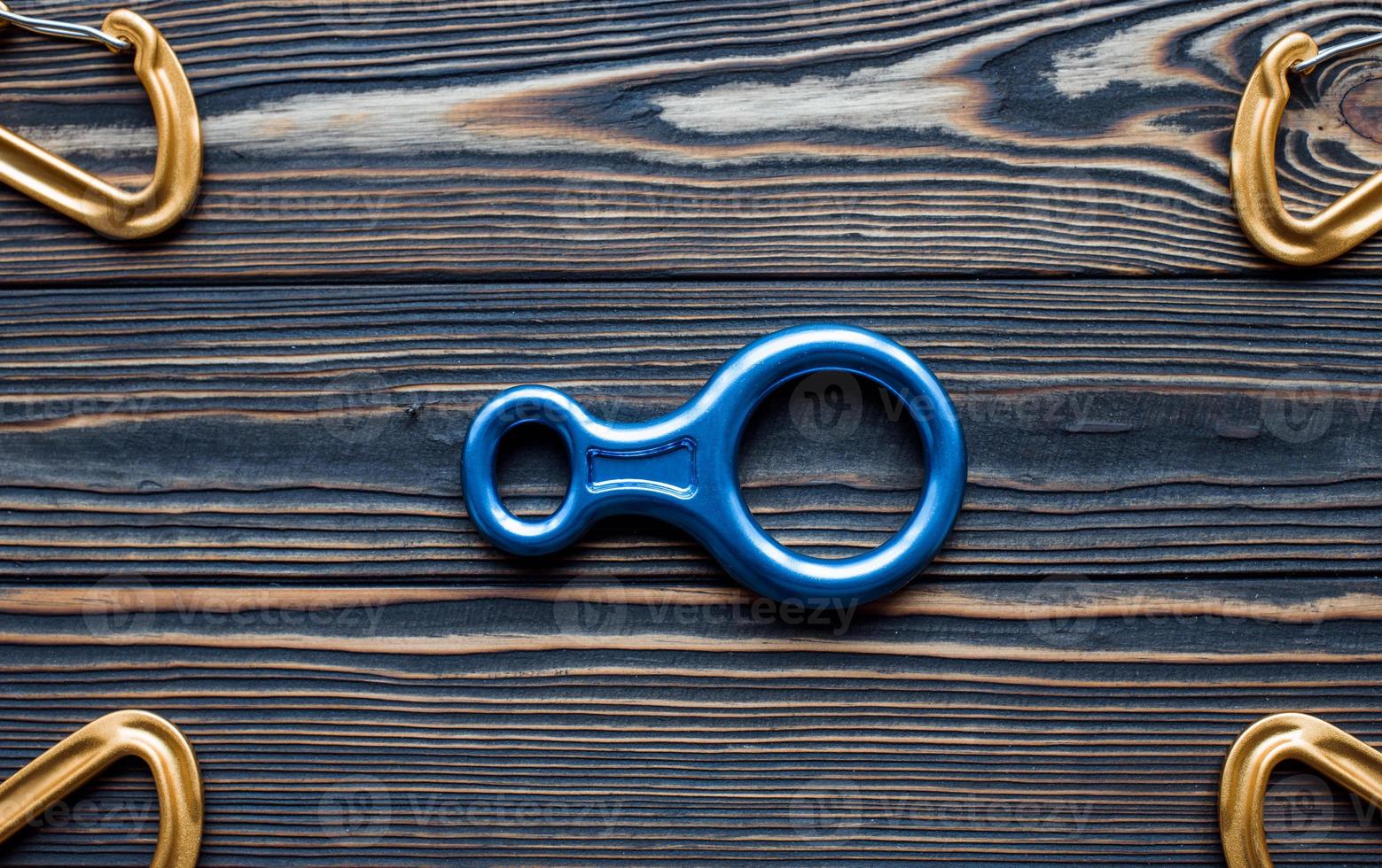 Blue and golden colored items. Isolated photo of climbing equipment. Parts of carabiners lying on the wooden table