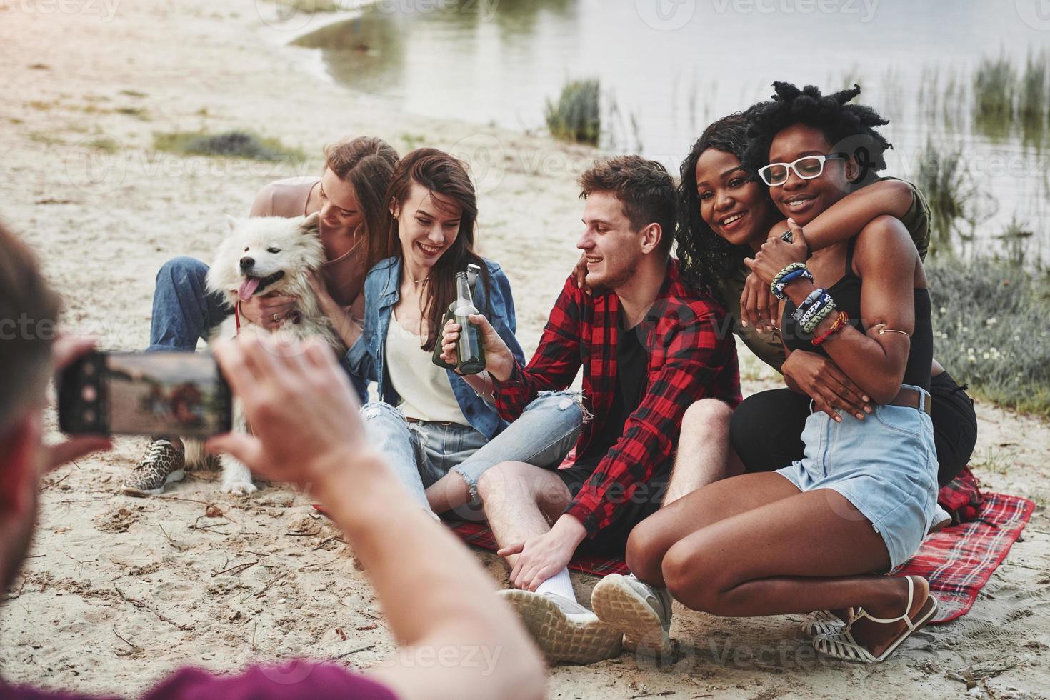 Wait, I'm focusing. Group of people have picnic on the beach. Friends have fun at weekend time photo