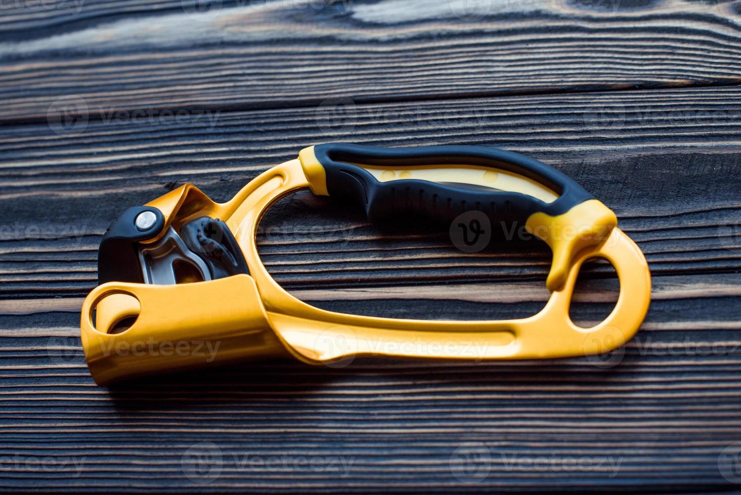 Golden colored tool. Isolated photo of climbing equipment. Part of carabiner lying on the wooden table