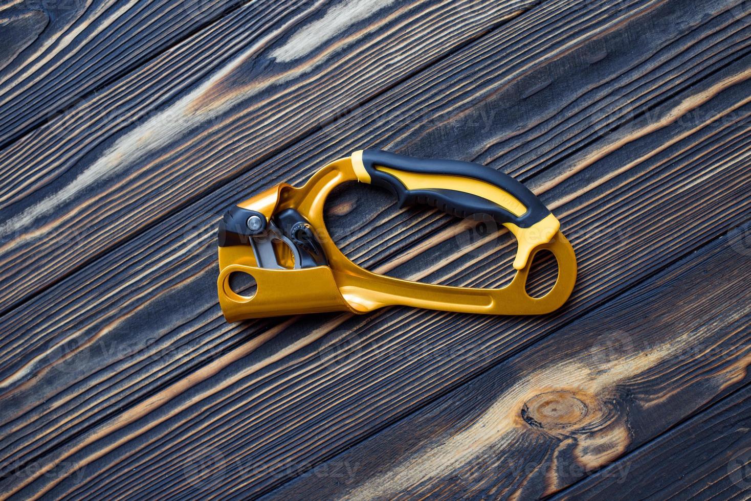 Top view. Isolated photo of climbing equipment. Part of carabiner lying on the wooden table