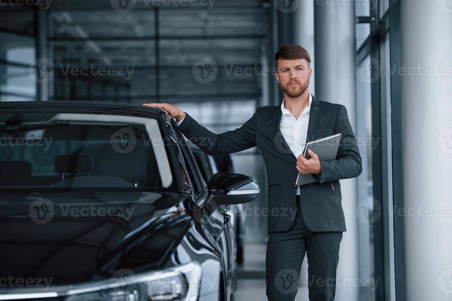 With silver note pad in hand. Modern stylish bearded businessman in the automobile saloon photo