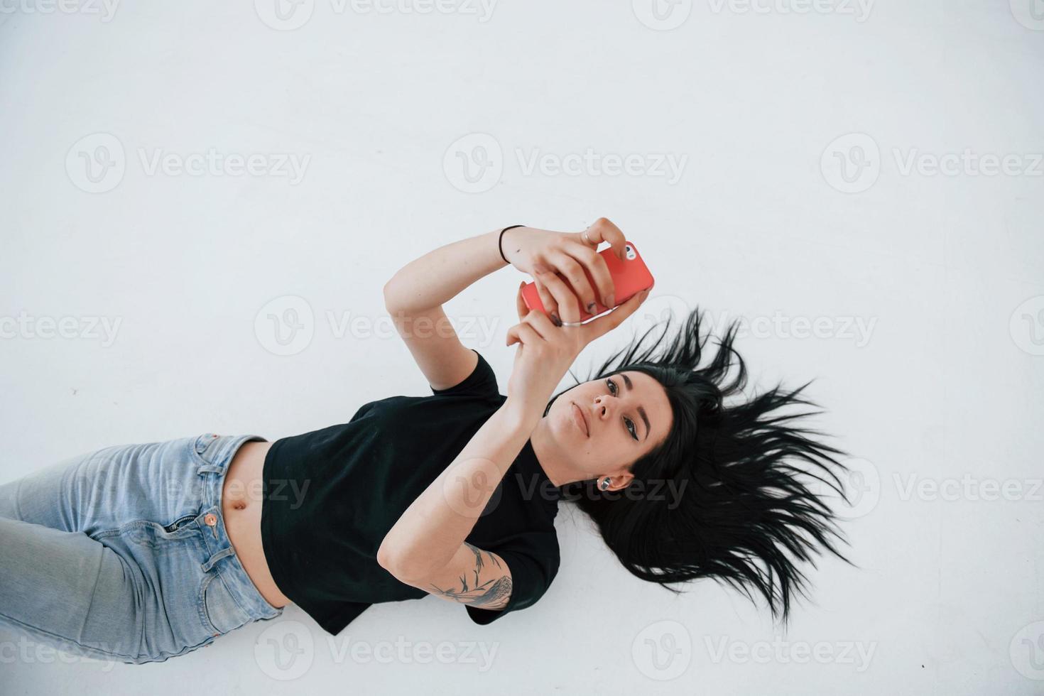 Using smartphone. Young female brunette teen have photoshoot in the studio at daytime photo