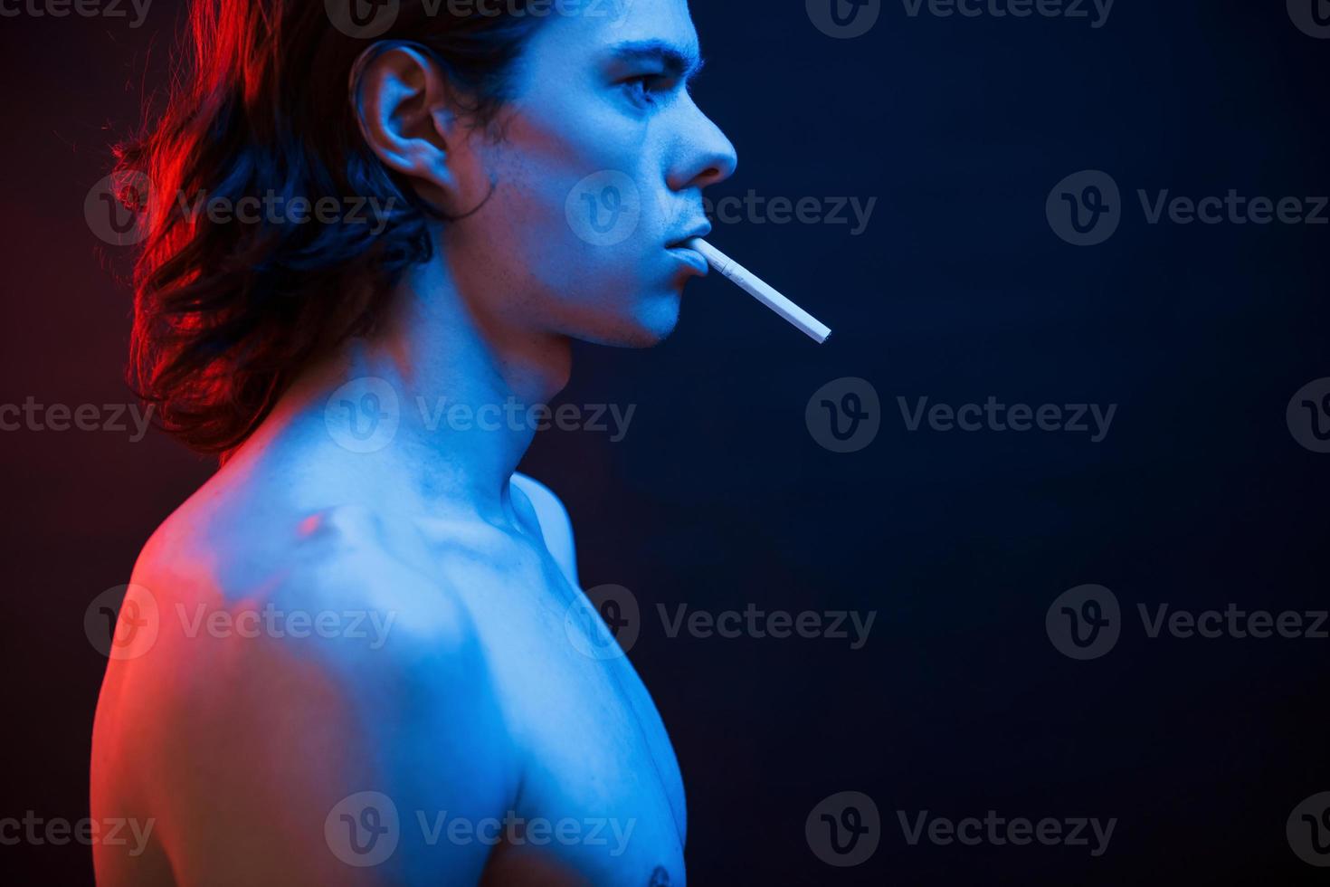 Good looking guy. Studio shot in dark studio with neon light. Portrait of serious man photo