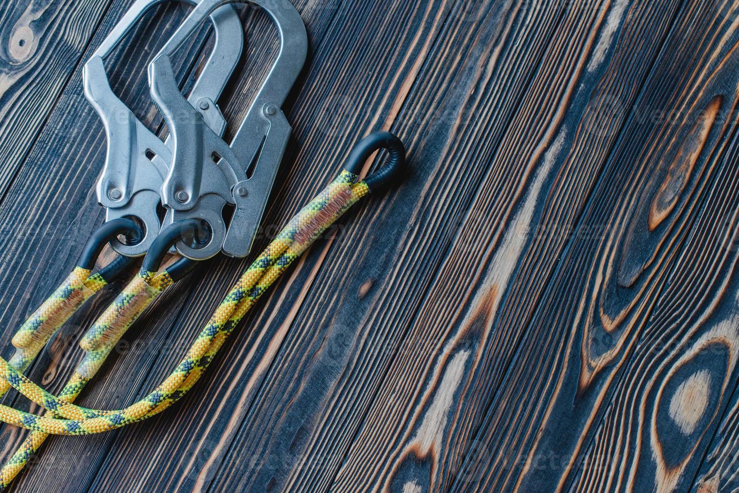 Helps in dangerous situations on mountains. Isolated photo of climbing equipment. Part of carabiner lying on the wooden table