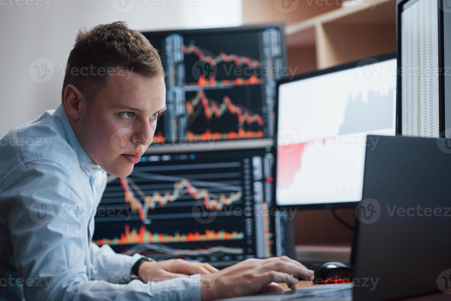 Laptop for daily job. Man working online in the office with multiple computer screens in index charts photo