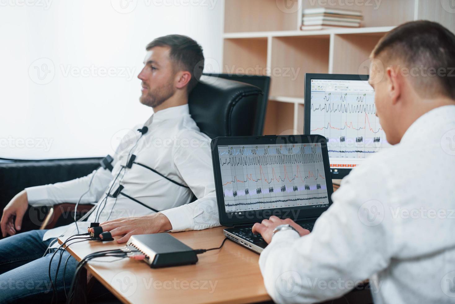 I wasn't be there. Suspicious man passes lie detector in the office. Asking questions. Polygraph test photo