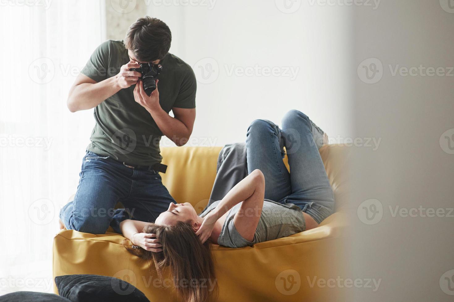 Relax and calm please. Photographer taking a shot of young girl that lying on the white sofa photo
