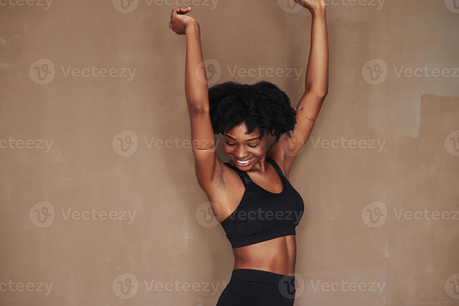 Happy girl. Young beautiful afro american woman in the studio against brown background photo