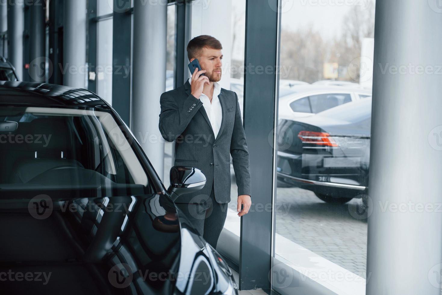 chico exitoso. hombre de negocios barbudo con estilo moderno en el salón del automóvil foto