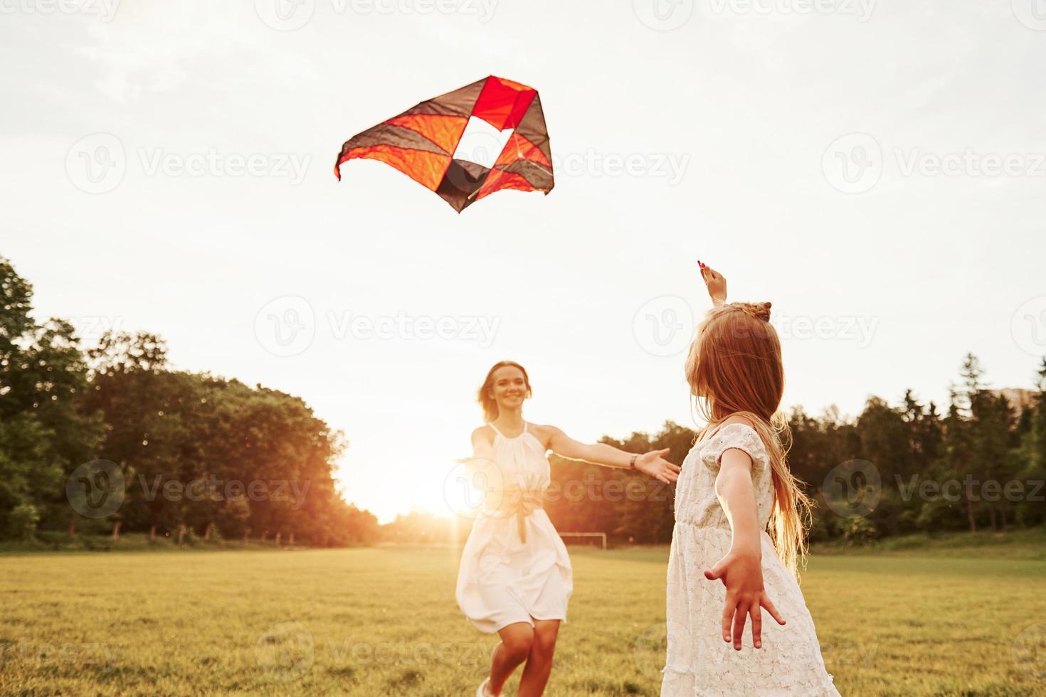 Time for a hugs. Mother and daughter have fun with kite in the field. Beautiful nature photo