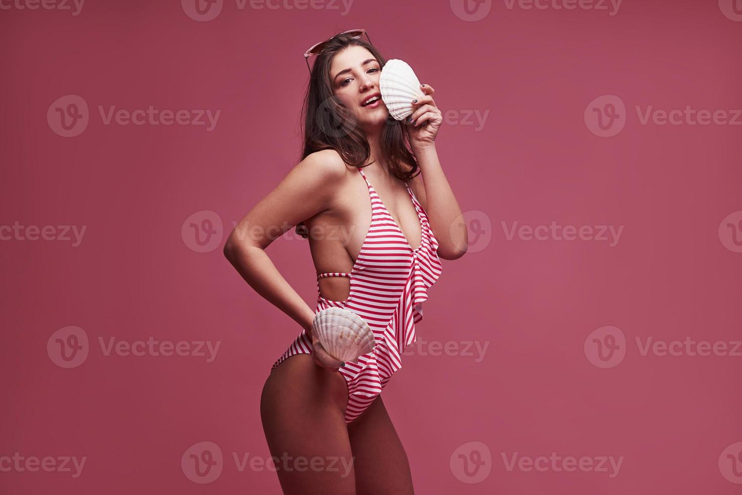 Two shellfish in the hands. Stylish beautiful young girl in bikini stands and posing in the studio photo