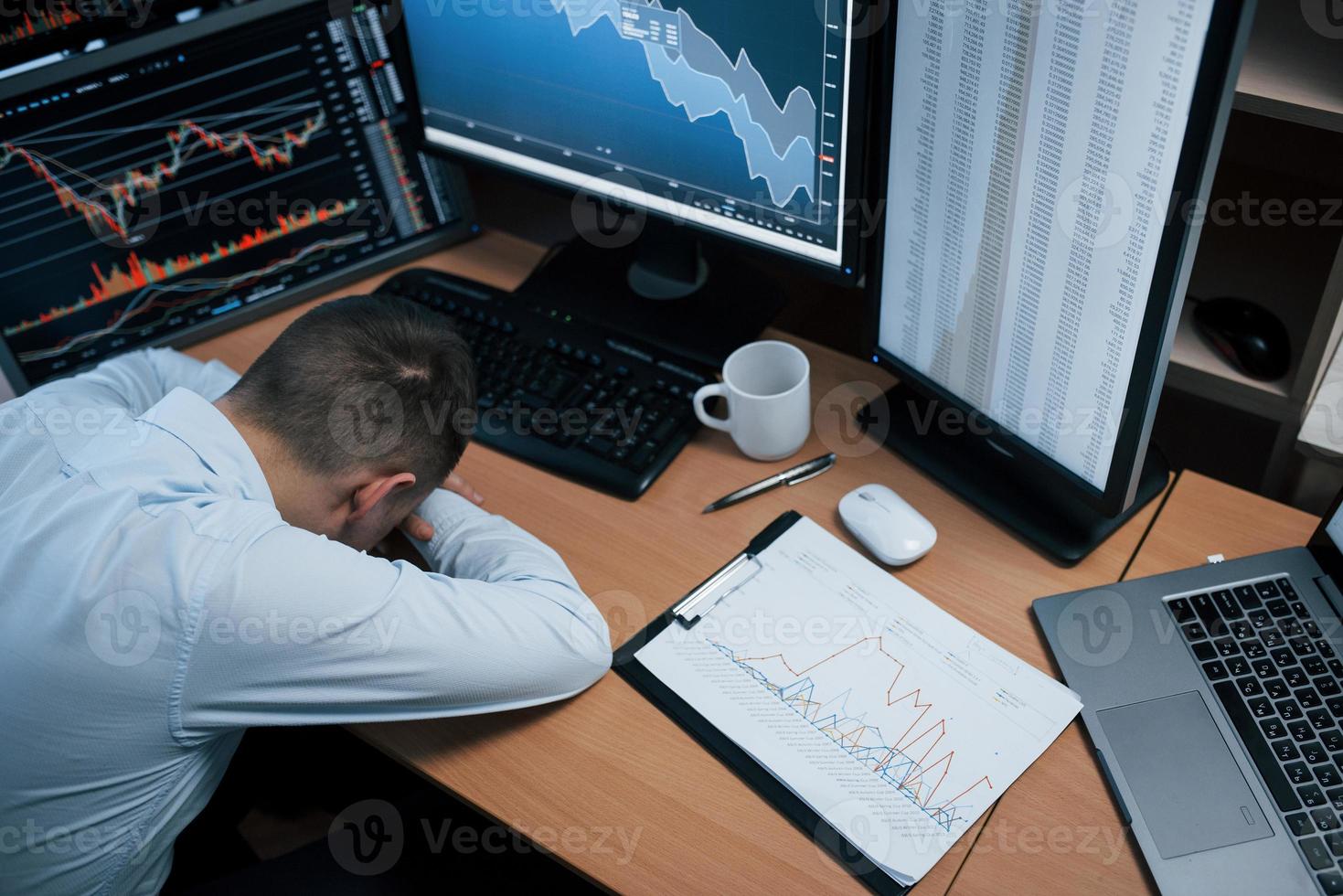 Psychological health conception. Modern anxiety and stress. Man working online in the office with multiple computer screens in index charts photo