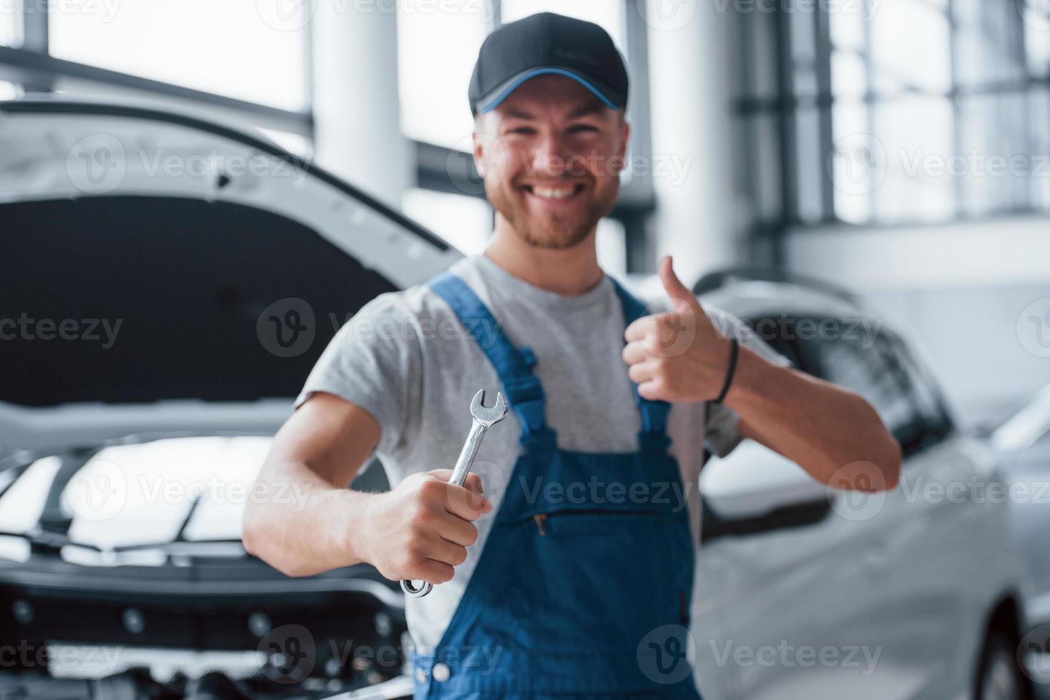 Your car is in good hands. Employee in the blue colored uniform stands in the automobile salon photo