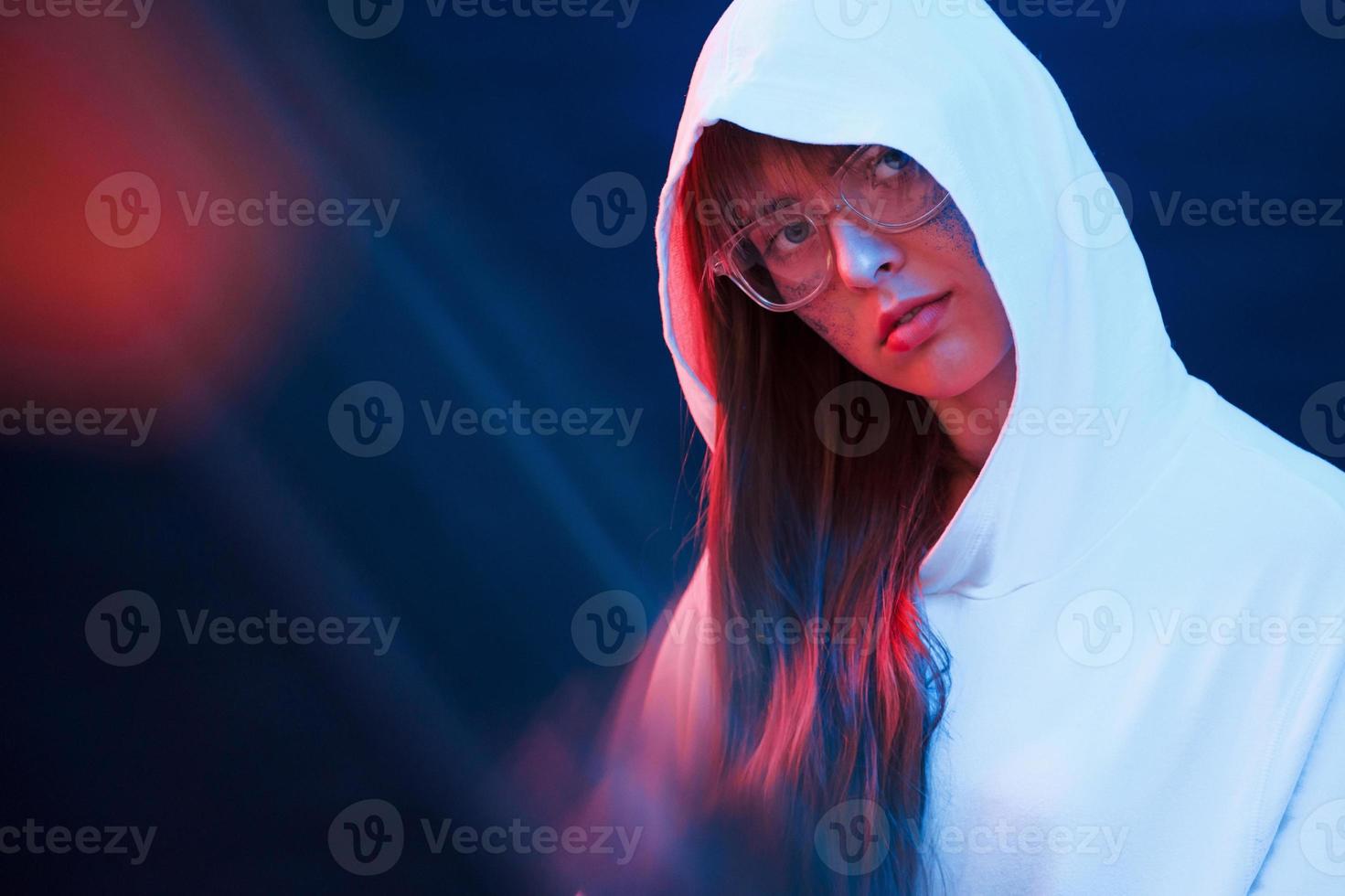 Caucasian ethnicity. Studio shot in dark studio with neon light. Portrait of young girl photo