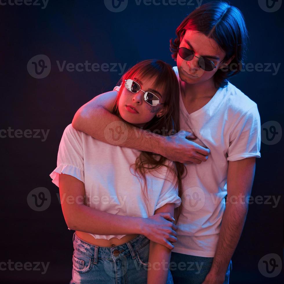 Lovely people. Couple standing in dark room with red and blue neon lighting photo